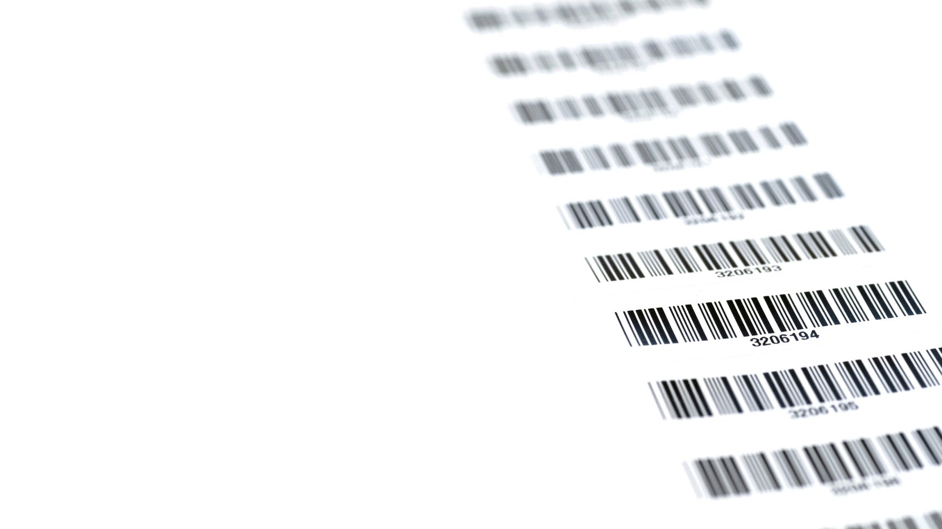 Mehrere schwarze Strichcodes sind untereinander auf einem weißen Blatt Papier abgedruckt. Der Fokus liegt scharf auf einem der mittleren Barcodes, während die restlichen nach oben und unten hin verschwimmen.