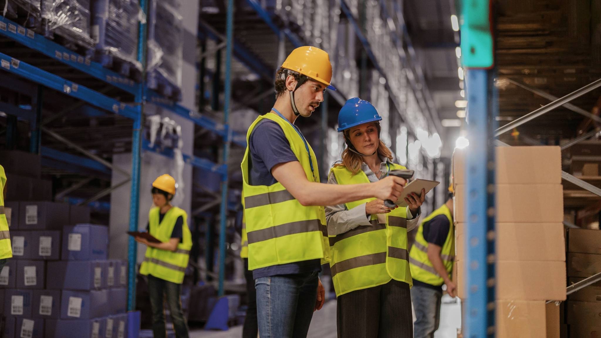 Mitarbeiter im Lager mit Warnweste und Scanner – Bestandsaufnahme und Paketlogistik im Industrieumfeld