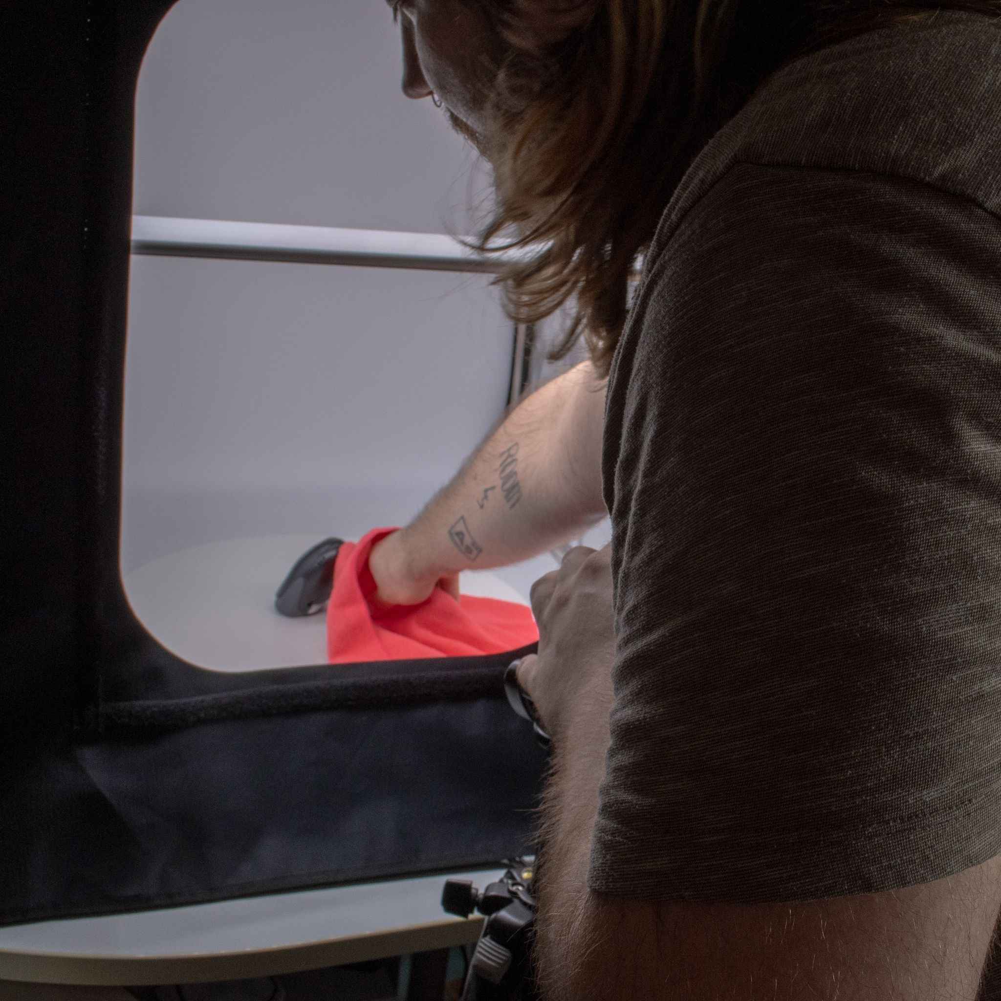 Fotograf richtet Produkt im Lichtzelt für professionelle Aufnahme aus – Vorbereitung eines Barcode-Scanners für den Onlineshop